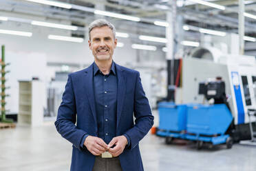 Portrait of smiling mature businessman in factory - DIGF18027