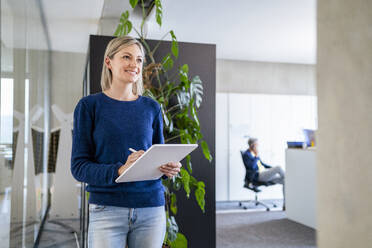 Lächelnde Geschäftsfrau mit digitalem Tablet im Büro - DIGF18055