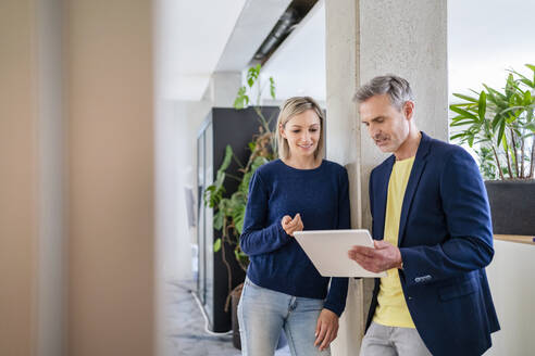 Businessman and businesswoman working together on digital tablet in office - DIGF18059