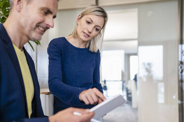 Businessman and businesswoman working together on digital tablet in office - DIGF18066