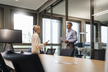 Businessman and businesswoman talking in office - DIGF18089