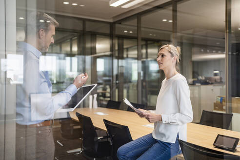 Businessman and businesswoman with digital tablet and documents talking in office - DIGF18090