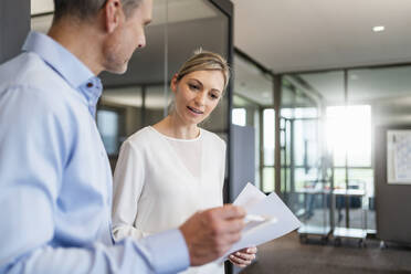 Businessman and businesswoman with digital tablet and documents talking in office - DIGF18093