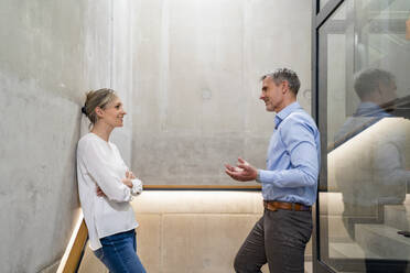 Businessman and businesswoman talking on stairs in office - DIGF18098