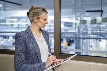 Businesswoman using digital tablet in factory office - DIGF18107