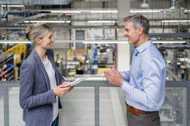 Businessman and businesswoman talking in factory - DIGF18116