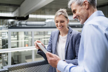 Businessman and businesswoman sharing digital tablet in factory - DIGF18120