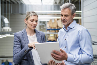 Businessman and businesswoman sharing digital tablet in factory - DIGF18121