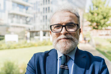 Senior businessman wearing eyeglasses standing at office park - MEUF06233