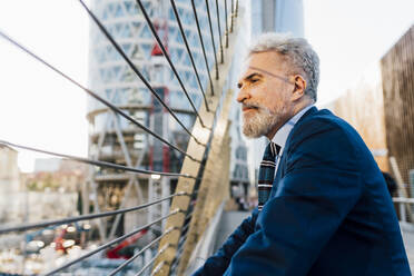 Senior businessman standing outside office building on sunny day - MEUF06321