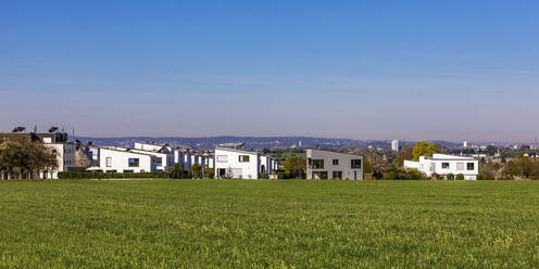 Deutschland, Baden-Württemberg, Waiblingen, Grüne Frühlingswiese vor modernen Vorstadthäusern - WDF06953