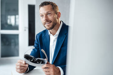 Lächelnder Geschäftsmann mit Virtual-Reality-Headset im Büro - MOEF04159