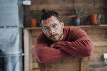 Mature man with eyeglasses sitting on chair - MOEF04171