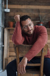 Man with eyeglasses sitting on chair - MOEF04172