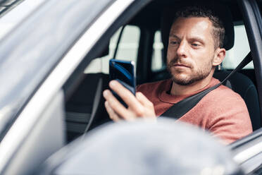 Man using smart phone sitting in car - MOEF04195