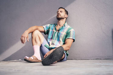 Mature man with eyes closed relaxing near concrete wall - MOEF04198