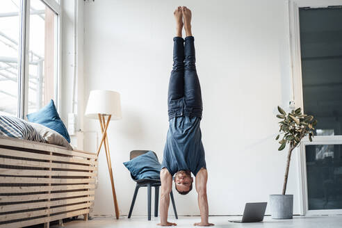 Mann übt Handstand vor einer Wand zu Hause - MOEF04219