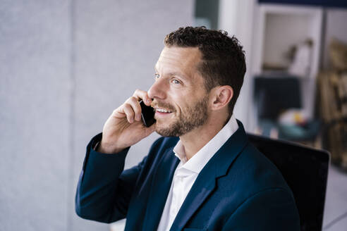 Lächelnder Geschäftsmann, der mit einem Smartphone telefoniert - MOEF04222