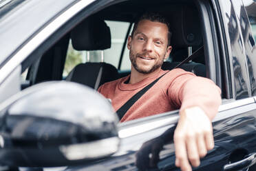 Lächelnder Mann im Auto sitzend - MOEF04255