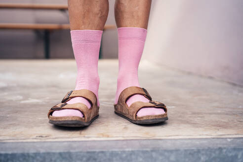 Beine eines auf dem Boden stehenden Mannes in rosa Socken und Sandalen - MOEF04264