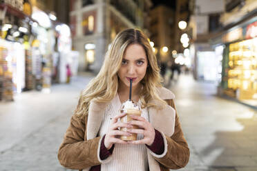 Junge Frau trinkt Kaffee auf der Straße in der Stadt - WPEF05974