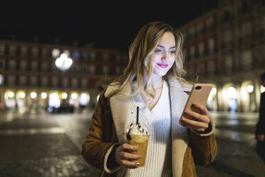 Frau mit Kaffeetasse und Smartphone in der Stadt - WPEF05975