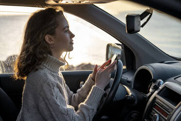 Lächelnde junge Frau mit Smartphone im Auto sitzend - VPIF06367