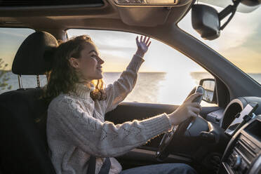 Happy young woman sitting on driver's seat in car - VPIF06369