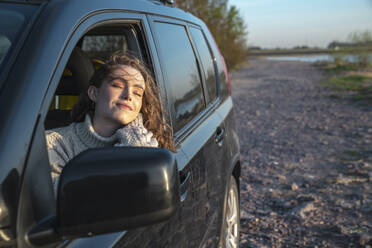 Smiling woman with eyes closed sitting in car - VPIF06370
