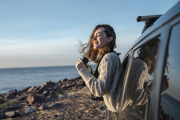 Happy woman with binoculars looking out of car window - VPIF06373