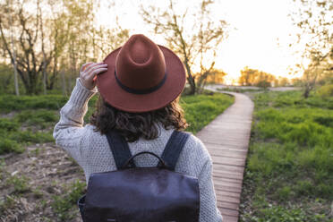 Woman wearing hat walking in park - VPIF06388