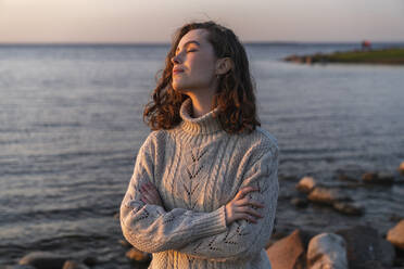 Smiling young woman with eyes closed enjoying sunset - VPIF06393