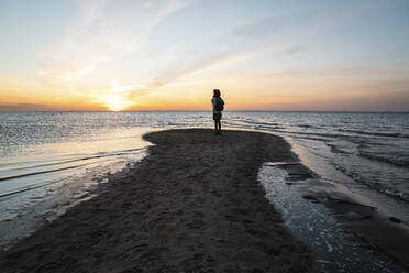 Woman standing on sea coast at sunset - VPIF06408