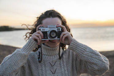 Lächelnde junge Frau, die durch die Kamera fotografiert - VPIF06412