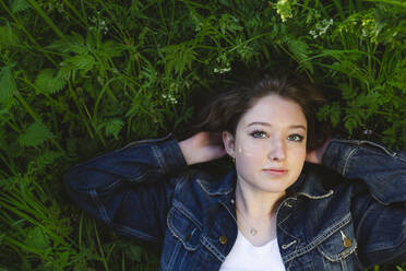 Teenager in denim jacket lying on grass - IHF00896