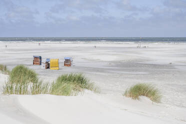 Deutschland, Niedersachsen, Juist, Strandkörbe mit Kapuze am leeren Strand mit klarer Linie des Horizonts über der Nordsee im Hintergrund - KEBF02320