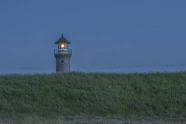 Germany, Lower Saxony, Juist, Grassy terrain in front of lighthouse at dusk - KEBF02333