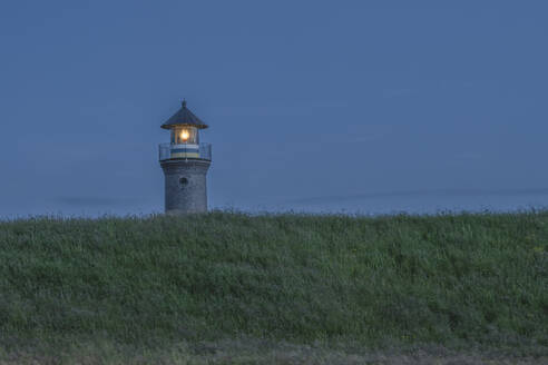 Deutschland, Niedersachsen, Juist, Grasbewachsenes Gelände vor Leuchtturm in der Abenddämmerung - KEBF02333