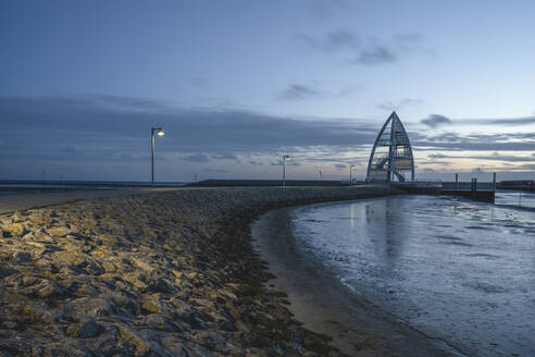 Deutschland, Niedersachsen, Juist, Leere Seebrücke in der Abenddämmerung mit Aussichtsturm im Hintergrund - KEBF02334