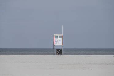 Deutschland, Niedersachsen, Juist, Rettungsschwimmerhütte am leeren Strand mit klarer Linie des Horizonts über der Nordsee im Hintergrund - KEBF02355