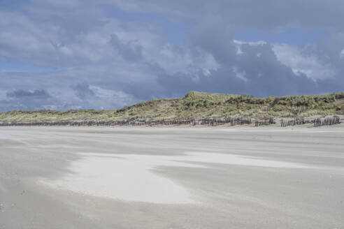 Deutschland, Niedersachsen, Juist, Leerer Strand im Sommer mit Dünen im Hintergrund - KEBF02356