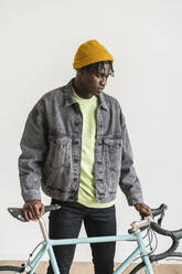 Junger Mann mit Fahrrad vor einer Hauswand - VPIF06461