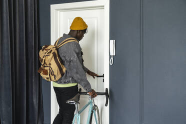 Studentin mit Fahrrad öffnet Tür zu Hause - VPIF06510