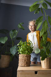 Glückliches Mädchen, das nach Pflanzen schaut, die zu Hause stehen - SVKF00279