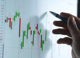 Händler, der im Büro Diagramme auf dem Bildschirm seines Geräts analysiert - ABRF00978