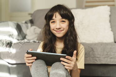 Lächelndes Mädchen mit Tablet-PC im Wohnzimmer - OSF00059