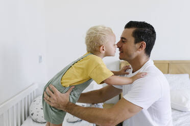 Mann reibt sich die Nase mit seinem Sohn im Bett zu Hause - TYF00224