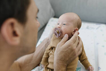 Mann hält Baby mit Schnuller zu Hause - TYF00239