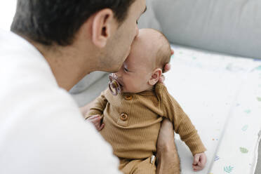 Father kissing baby on forehead at home - TYF00240