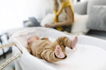 Baby schläft im Kinderbett, während die Mutter zu Hause arbeitet - TYF00242